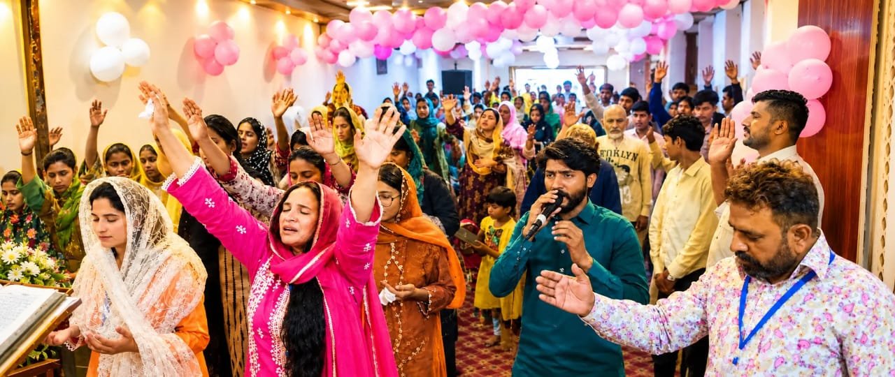 Congregation raising hands in joyful worship at Church of Christ Assembly in Pakistan